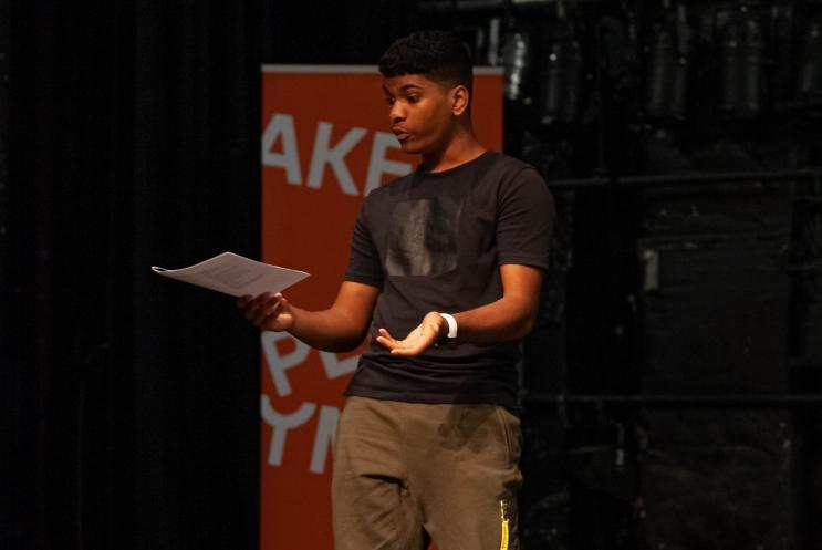 Young man reading from a script on stage